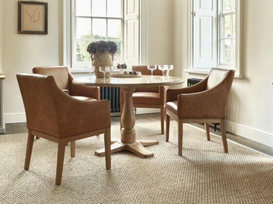 A dining table and dining chairs-dining room furniture-tan leather dining chair-round dining table-glassware-sisal rug-neutral walls-sideboard-dresser