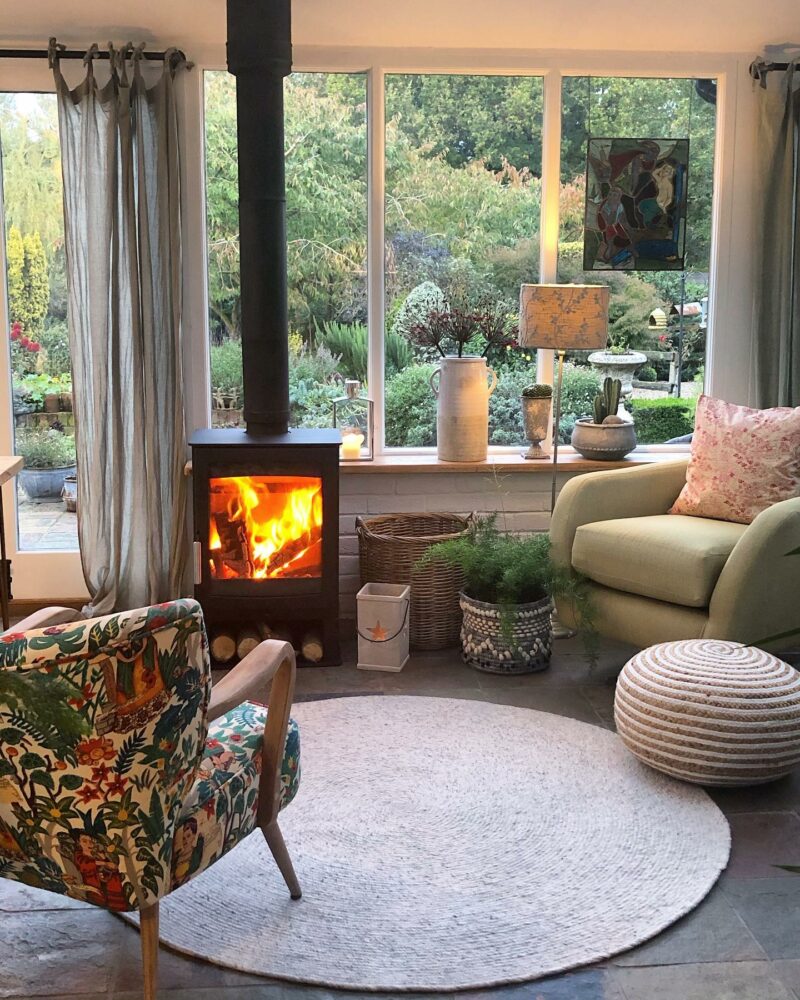 Pale green Evie swivel chair in a cosy setting next to a wood-burning stove.