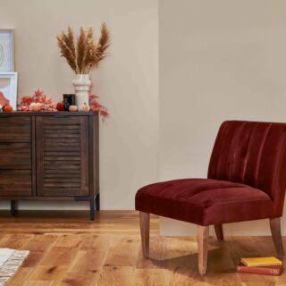 Burgundy velvet accent chair with oak legs in a room with a dark oak and metal sideboard and coffee table.