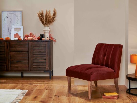 Burgundy velvet accent chair with oak legs in a room with a dark oak and metal sideboard and coffee table.