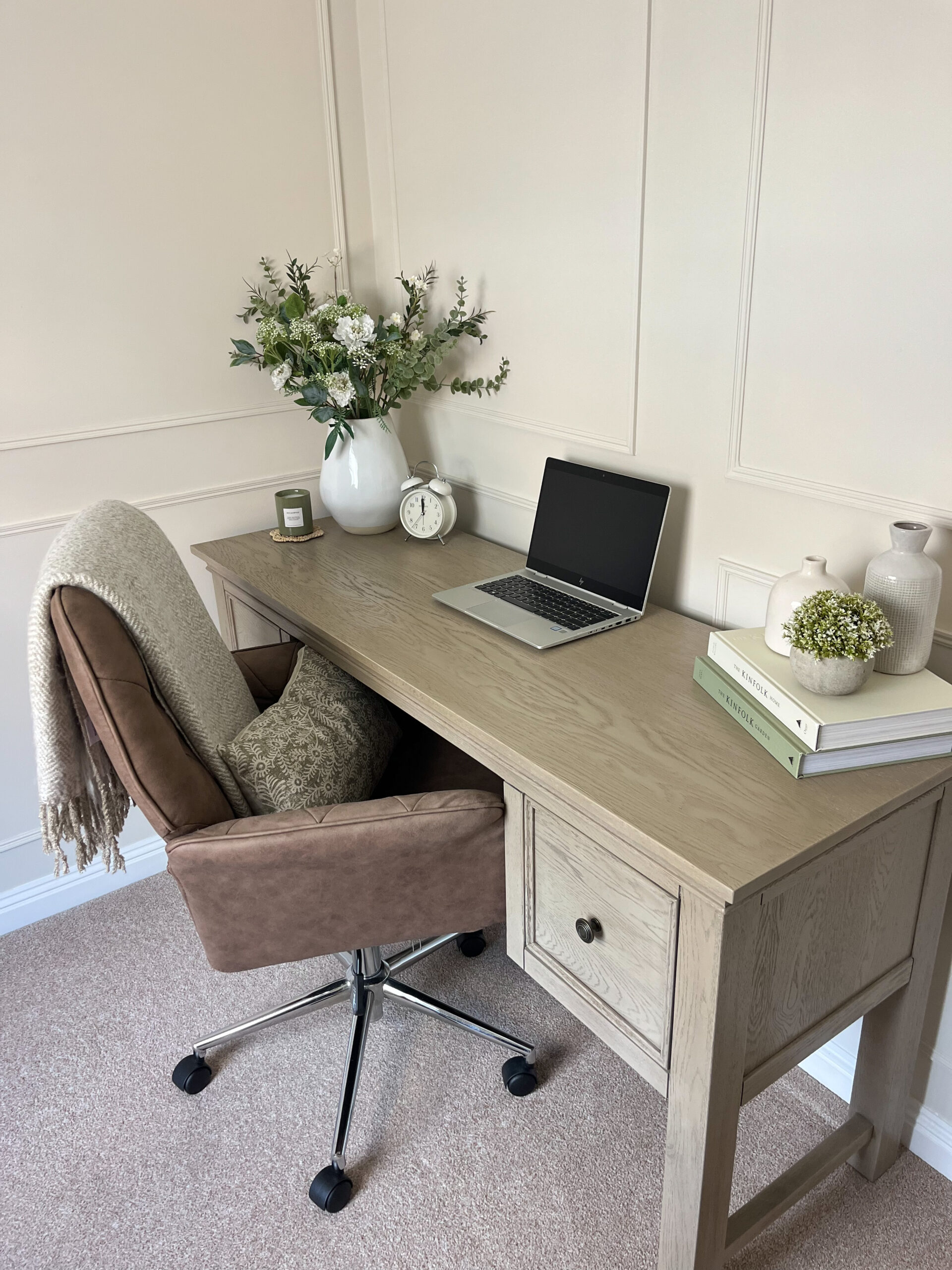 A desk and chair-home office furniture-weathered oak desk-office swivel chair-white vase with flowers-laptop-stack of books