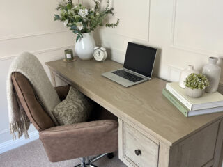 A desk and chair-home office furniture-weathered oak desk-office swivel chair-white vase with flowers-laptop-stack of books