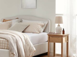 A bed and bedside table-bedroom furniture-upholstered bed-neutral walls-wooden bedside table