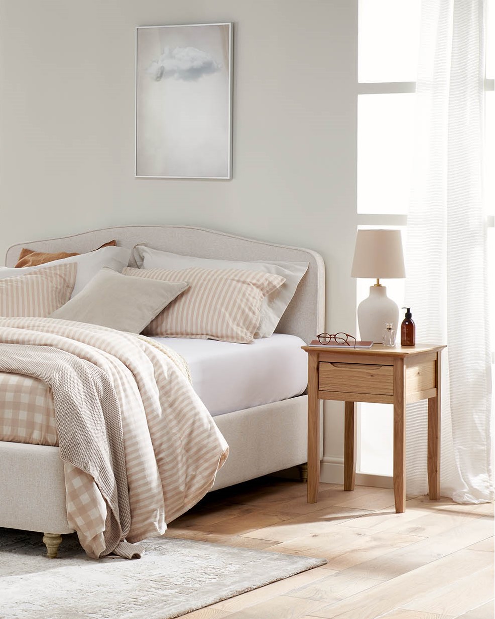 A bed and bedside table-bedroom furniture-upholstered bed-neutral walls-wooden bedside table