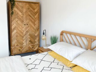 A bed, beside table and wardrobe-bedroom furniture-monochrome and yellow bedding-wooden bedside table-wooden triple wardrobe-wooden bed-bulb lamp