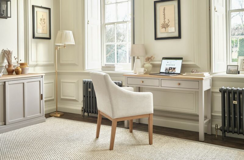 A desk, upholstered chair and sideboard-home office furniture-wooden desk painted neutral-neutral walls-cream upholstered chair-wooden sideboard painted neutral-floor standing lamp