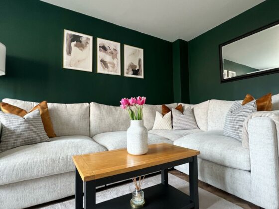 A corner sofa and coffee table-living room furniture-beige corner sofa-scatter cushions-dark green walls-wall art-horizontal mirror-black coffee table