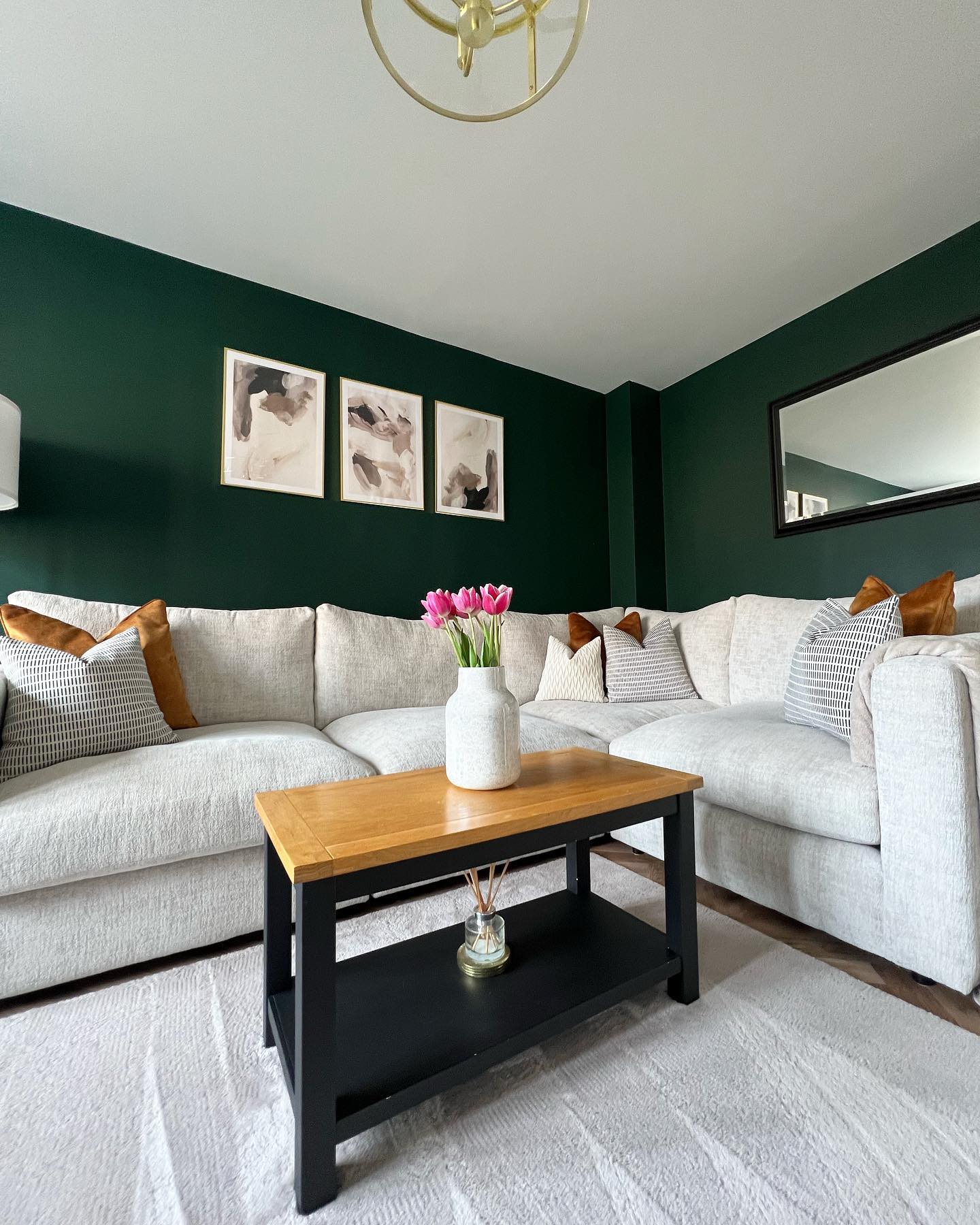 A corner sofa and coffee table-living room furniture-beige corner sofa-scatter cushions-dark green walls-wall art-horizontal mirror-black coffee table