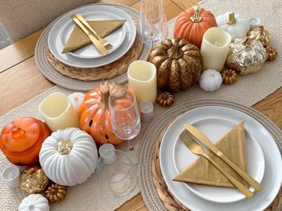 A dining table and chair-dining room furniture-pumpkin display-gold cutlery-white crockery-neutral table runner-champagne glasses-candles-wooden dining table-neutral dining chair