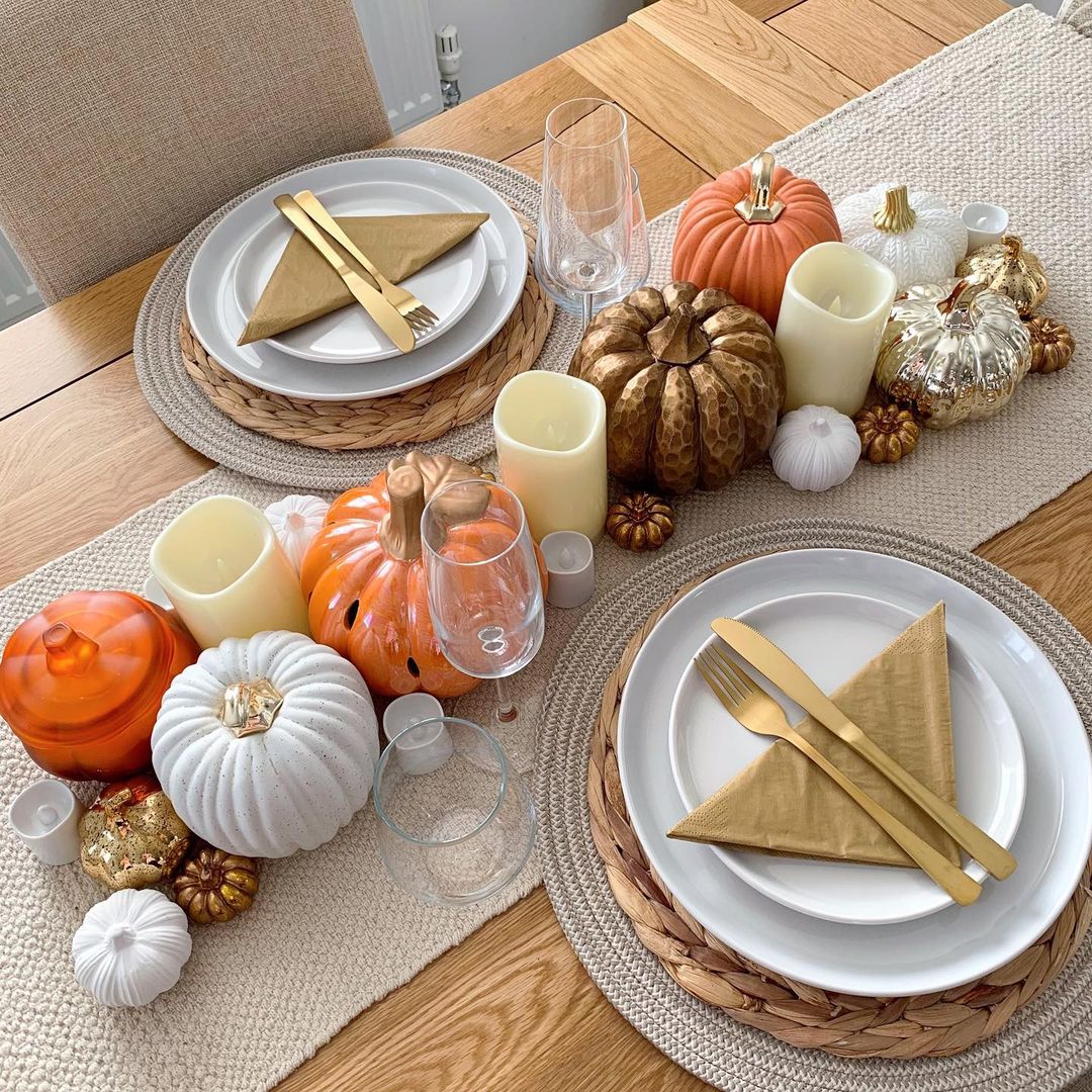 A dining table and chair-dining room furniture-pumpkin display-gold cutlery-white crockery-neutral table runner-champagne glasses-candles-wooden dining table-neutral dining chair