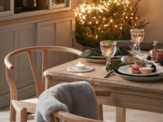 A dining table, dining chairs and dresser-dining room furniture-neutral walls-wooden dining table-wooden wishbone style dining chairs-textured rug-Christmas dining tablescape-scandinavian design-wooden grey mirror-Christmas fireplace-Christmas tree