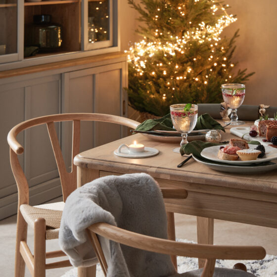 A dining table, dining chairs and dresser-dining room furniture-neutral walls-wooden dining table-wooden wishbone style dining chairs-textured rug-Christmas dining tablescape-scandinavian design-wooden grey mirror-Christmas fireplace-Christmas tree