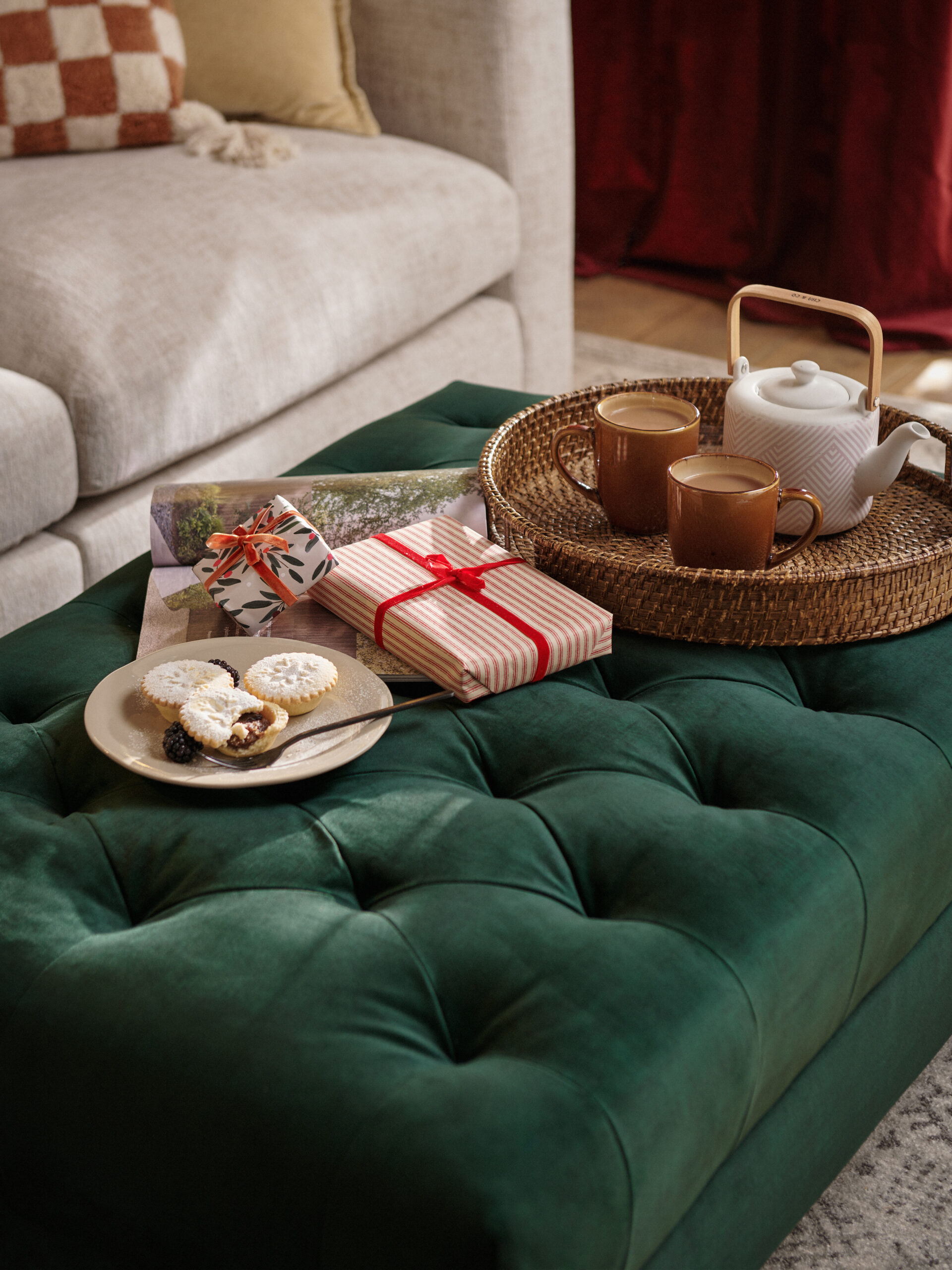 A sofa and footstool-living room furniture-yellow walls-velvet footstool-neutral cosy sofa-wicker tea tray-mince pies-wrapped presents