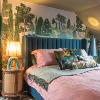 A bed and bedside table-bedroom furniture-forest wall mural-teal upholstered bed-pink bedding-statement lamp-wooden bedside table-storage bed